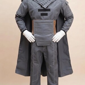 May include: A gray costume with a long coat, pants, and a structured top. The outfit features white stitching and a brown belt. The mannequin is wearing white gloves.
