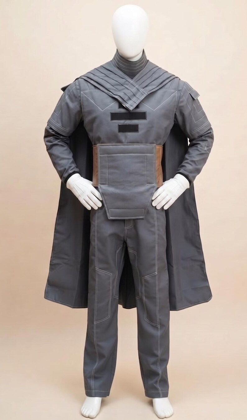 May include: A gray costume with a long coat, pants, and a structured top. The outfit features white stitching and a brown belt. The mannequin is wearing white gloves.