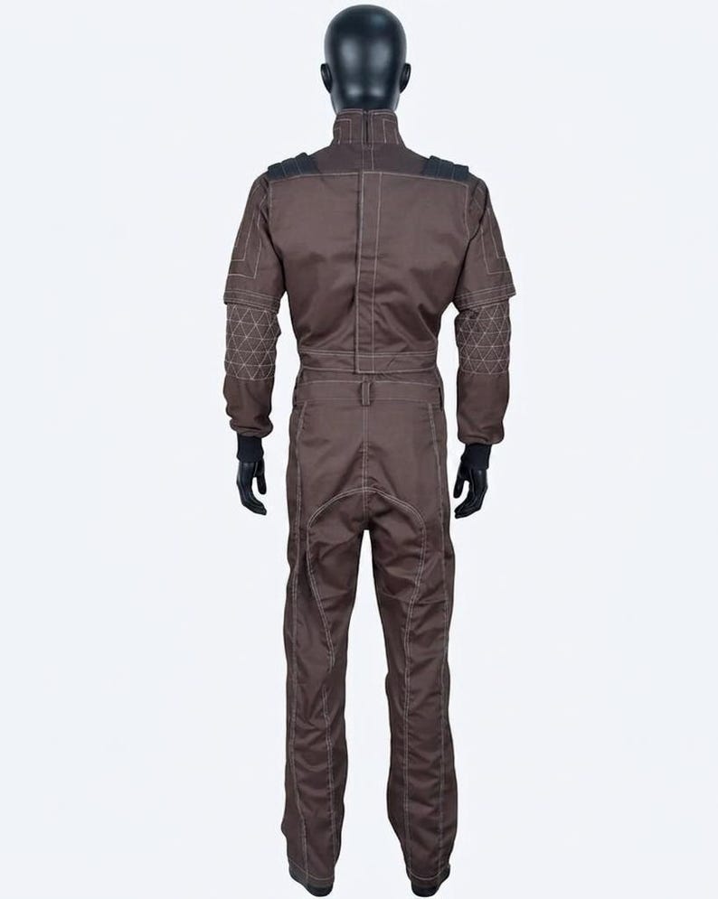 May include: A brown jumpsuit with white stitching details, displayed on a mannequin. The suit features black accents on the shoulders and geometric patterns on the sleeves. The mannequin is wearing black gloves.