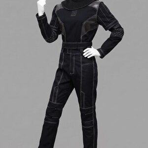Peut inclure: Combinaison noire avec des d&eacute;tails de couture blancs. Col montant, empi&egrave;cements aux &eacute;paules et ceinture. Le haut &agrave; manches longues pr&eacute;sente des coutures d&eacute;coratives sur les manches. Le pantalon a des d&eacute;tails aux genoux et aux poches.