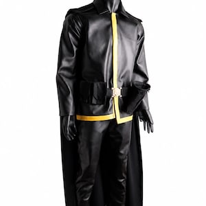 May include: A black faux leather jacket and matching trousers set featuring a yellow vertical stripe along the front closure and hem. The outfit includes a black cape, a black utility belt with a central gold buckle, and attached black pouches.