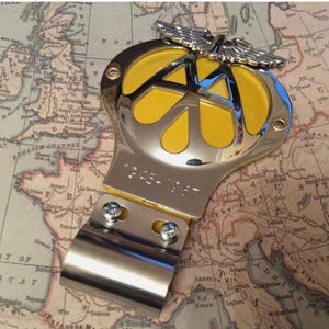 May include: A classic AA badge in chrome and yellow, displaying the AA logo and wings, with the years 1945-1967. The badge is positioned on a vintage map of Europe.