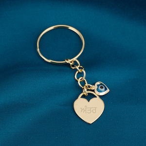 May include: Gold-tone keychain with a heart-shaped charm engraved with the word "m33" and a blue evil eye charm.