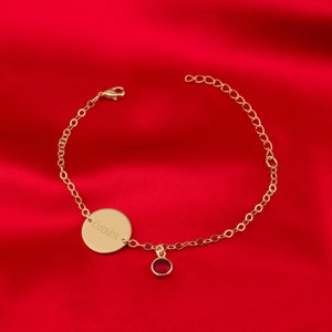 a gold bracelet with a disc on a red background