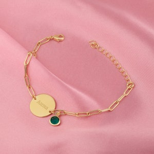 a gold bracelet with a green stone on it