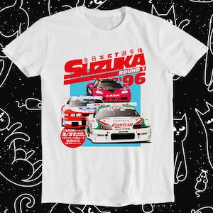 May include: White t-shirt featuring a graphic of three racing cars from the 1996 Suzuka Round 1 of the All Japan GT Championship. The text "Suzuka Round 1 '96" is in red and the text "全日本GT選手権" is in black. The text "三重県サーキット 3/31 Sunday エキサイティングなレース 8800" is in a white box.