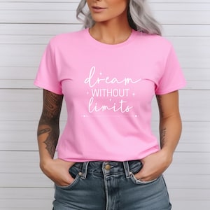 K&ouml;nnte beinhalten: Ein pinkfarbenes T-Shirt mit dem wei&szlig;en Schriftzug "dream without limits". Der Text ist kursiv geschrieben. Das Rundhals-T-Shirt wird mit einer blauen Jeans kombiniert. Der Text ist mittig auf der Vorderseite des T-Shirts platziert.