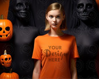 May include: A woman wearing an orange t-shirt with the text "YOUR Design HERE" printed on the front. She is standing in front of a black background with Halloween decorations.