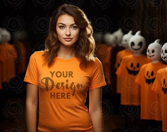 May include: A woman wearing an orange t-shirt with the text "YOUR Design HERE" printed on the front. She is standing in front of a dark background with Halloween decorations.
