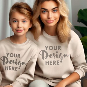Pode incluir: Duas pessoas vestindo moletons bege com o texto "YOUR DESIGN HERE" estampado na frente. As pessoas estão sorrindo e olhando para a câmera.