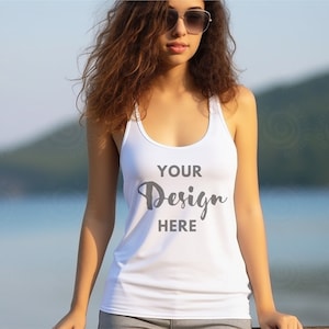 Op de afbeelding: Een wit tanktop met de tekst "YOUR Design HERE" erop gedrukt. Het tanktop wordt gedragen door een persoon met lang bruin haar en een zonnebril.