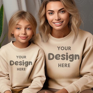 Pode incluir: Duas pessoas vestindo moletons bege com o texto "YOUR DESIGN HERE" estampado na frente. Os moletons são um conjunto combinando.