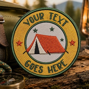 May include: Embroidered patch with a camping tent design. The patch is round, with a yellow border and green trim. The text "YOUR TEXT GOES HERE" is embroidered around the edge. The tent is red and white, with stars.