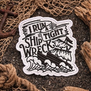 Puede incluir: Parche bordado con el texto "I Run a Tight Ship Wreck" en negro sobre fondo blanco. El diseño incluye un barco, olas y una pancarta. El parche tiene un borde blanco y es probablemente para ropa o accesorios.