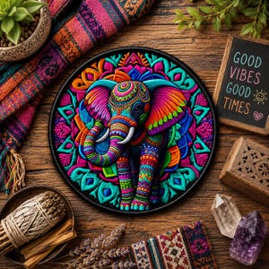 May include: A vibrant, embroidered elephant patch with a detailed mandala design. The elephant is adorned with colorful patterns in shades of blue, pink, orange, and green. The patch is surrounded by a black border and sits on a wooden surface.