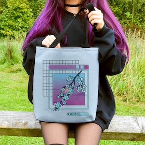 May include: A sky blue tote bag with a graphic of a flower branch in a computer window. The text "みいさくら" is at the bottom of the window. The bag is small and the model is 4' 9"/146cm.