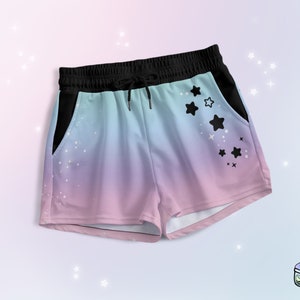 May include: A pair of pastel pink and blue athletic shorts with a black waistband and drawstring. The shorts have black star designs on the right side and a black pocket on the left side.
