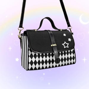 May include: Black and white crossbody bag with a top handle and adjustable strap. The bag features a black flap with white star designs and a black and white diamond pattern. The sides have vertical white stripes.