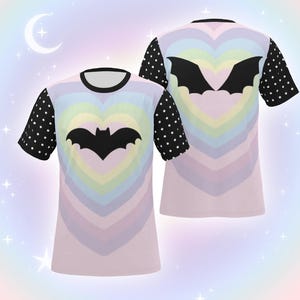 May include: Two t-shirts with a pastel rainbow heart design and a black bat silhouette in the center. The sleeves are black with white polka dots. The shirts have a black collar.