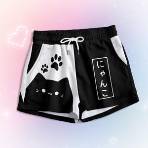 May include: Black and white shorts with a cat face and paw prints on one side and the Japanese text "にゃん  " on the other side.