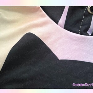 May include: Close-up of a black, white, and light pink hoodie. The design features a large black shape on the front, with a light pink band around the hood. The text "Chonk KitTea" is visible in the lower right corner.