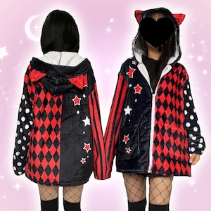 Könnte beinhalten: Zwei Kapuzenjacken mit einzigartigem Design. Eine Seite hat ein schwarz-rotes Rautenmuster, während die andere einen schwarzen Hintergrund mit roten Sternen hat. Eine Jacke hat einen gepunkteten Ärmel. Beide haben rote Katzenohren auf der Kapuze.
