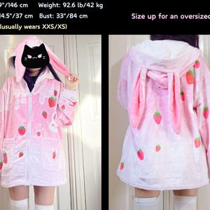 Puede incluir: Sudadera de felpa rosa con un dise&ntilde;o de fresa y conejo. La sudadera tiene una cremallera y una capucha con orejas de conejo. La sudadera se muestra en una modelo que lleva calcetines blancos y medias blancas.