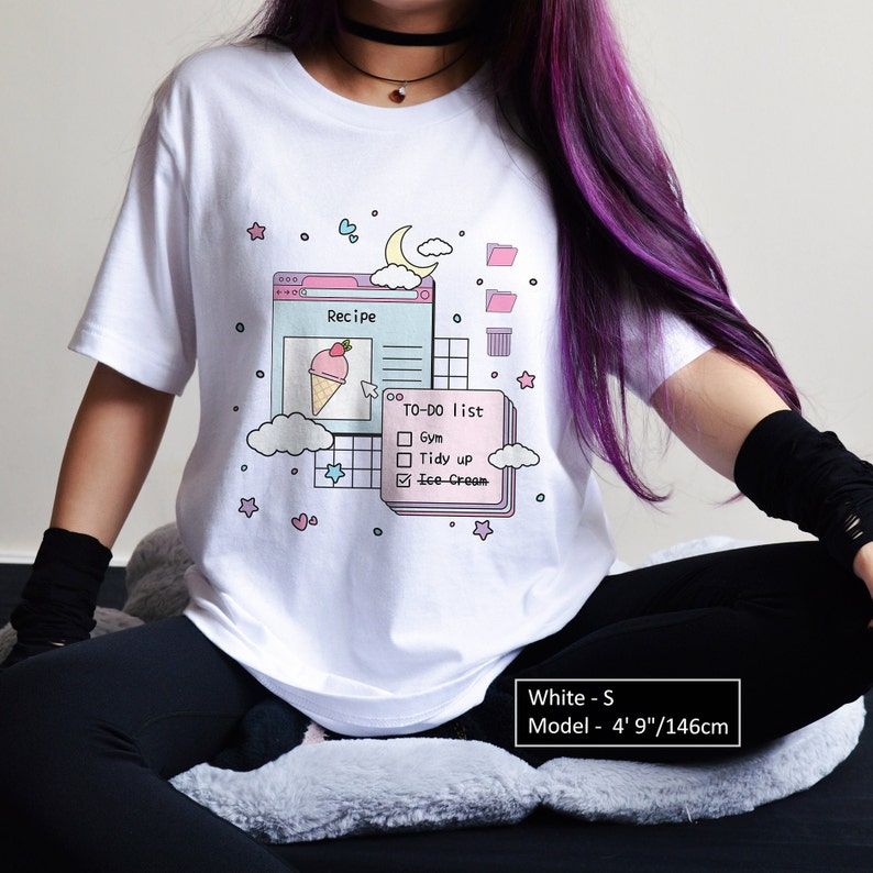 May include: White t-shirt featuring a graphic of a computer screen with a pink and blue ice cream cone, a recipe, and a to-do list. The graphic also includes clouds, stars, and hearts. The text on the shirt reads "Recipe" and "TO-DO list".