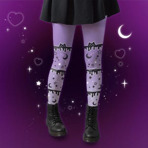 Może przedstawiać: Lawendowe legginsy z czarnym kotem i kroplami na g&oacute;rze oraz wzorem gwiazd i księżyc&oacute;w. Legginsy są połączone z czarnymi butami. Tło to fioletowy gradient.