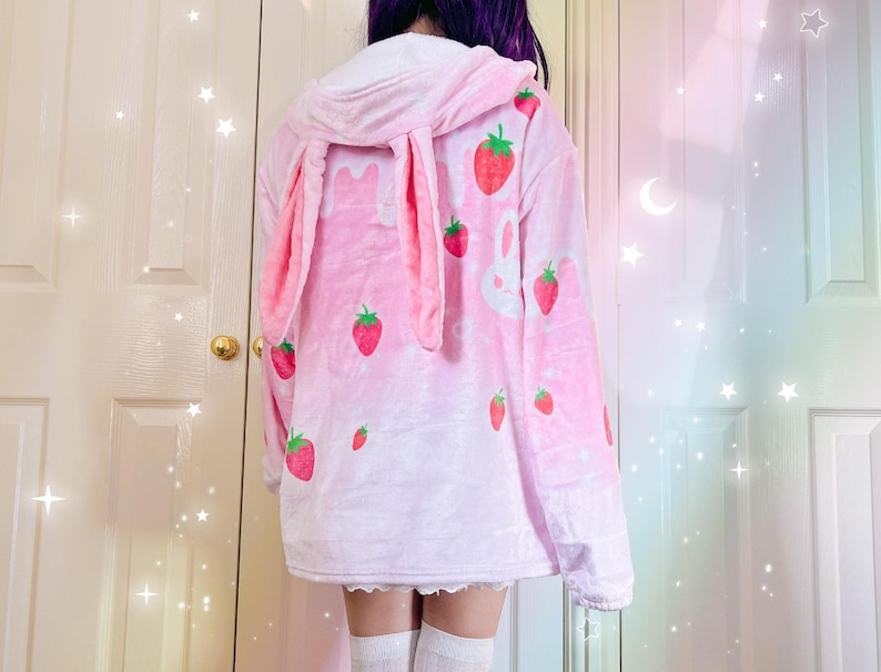 a girl wearing a fluffy pink bunny hoodie with hanging bunny ears in the hood, cute strawberry milk themed