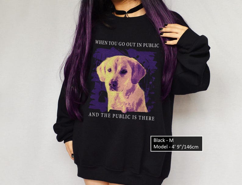 May include: Black sweatshirt with a graphic of a yellow labrador retriever and the text "WHEN YOU GO OUT IN PUBLIC AND THE PUBLIC IS THERE". The model is 4' 9" tall and wearing a size M.