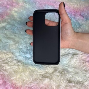 Op de afbeelding: Een zwarte telefoonhoes met een verhoogde camerabult. De hoes is gemaakt van glad, mat materiaal.
