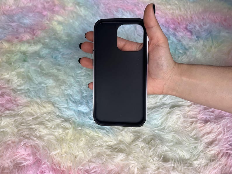 Op de afbeelding: Een zwarte telefoonhoes met een verhoogde camerabult. De hoes is gemaakt van glad, mat materiaal.