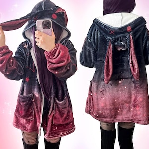 A girl wearing a fluffy black to red gradient zip up hoodie with bunny ears, view from the front and back, with red stars, cross, and small white sparkles