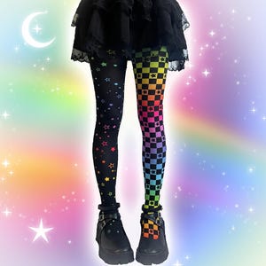 May include: Leggings featuring a split design with a black base covered in multicoloured stars on the left leg and a rainbow-coloured checkered pattern with small black stars on the right leg, paired with a black ruffled skirt and black buckled shoes.