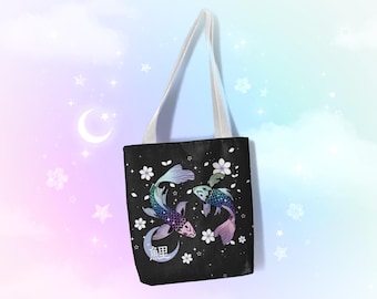 May include: A black tote bag with white straps features a design of two iridescent koi fish swimming in a circle with cherry blossoms and a crescent moon. The text "黒" is printed on the bag.