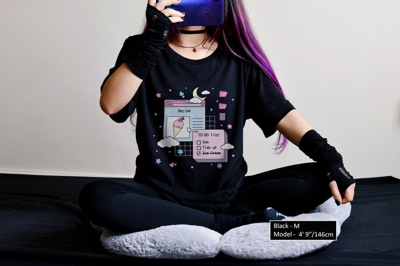 May include: Black t-shirt featuring a graphic of a computer screen with a recipe and a to-do list. The graphic includes a pink ice cream cone, a moon, and stars. The text on the shirt reads "Recipe" and "TO-DO list".
