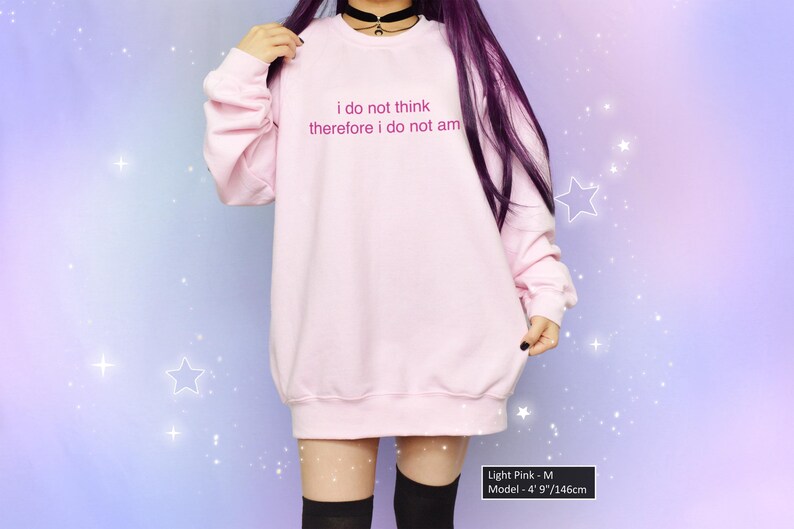 May include: Light pink sweatshirt with the text "i do not think therefore i do not am" in a soft, rounded font. The model is wearing a black choker. The background is a gradient of purple and blue with white star accents.