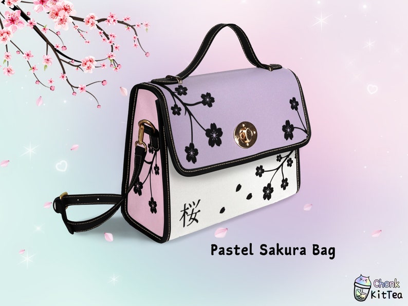 May include: Pastel pink and purple satchel bag with a black floral design and a gold clasp. The bag has a black adjustable shoulder strap and the text "桜" is printed on the front.