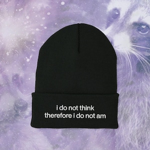 May include: Black beanie with white text that reads "i do not think therefore i do not am"