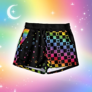 May include: Black shorts featuring a split design with a rainbow checkered pattern on one side and a black background with scattered colourful stars on the other. The shorts include an elastic waistband with a drawstring and side pockets.