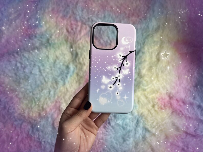 Op de afbeelding: Een witte telefoonhoes met een paarse en roze ombre achtergrond. De hoes heeft een zwart silhouet van een tak met witte bloemen en vlinders. De achtergrond is bedekt met kleine witte sterren.