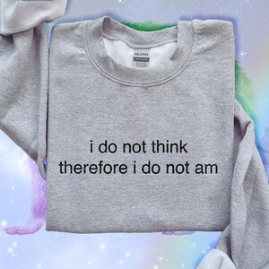 May include: A heather gray sweatshirt with the text "i do not think therefore i do not am" in black. The sweatshirt is folded, with the sleeves visible. The background is a colorful, galaxy-themed design.
