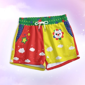 May include: Colorful shorts with a whimsical design. The shorts feature a red and yellow split design with cloud and star graphics. A green waistband and a white drawstring complete the look. A flower-shaped clown face is on the yellow side.