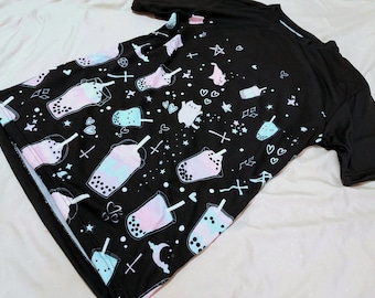 May include: Black t-shirt with a repeating pattern of pastel pink and blue boba tea cups with white outlines and various other small graphic elements like stars, hearts, and crosses.
