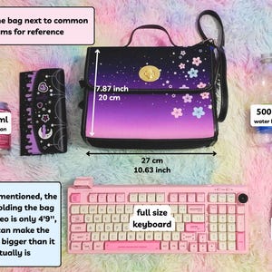 May include: A purple and black shoulder bag with a floral print and a gold clasp. The bag is next to a 330 ml soda can, a wallet, a full-size keyboard, a gaming mouse, and a 500 ml water bottle. The bag measures 7.87 inches tall and 10.63 inches wide.