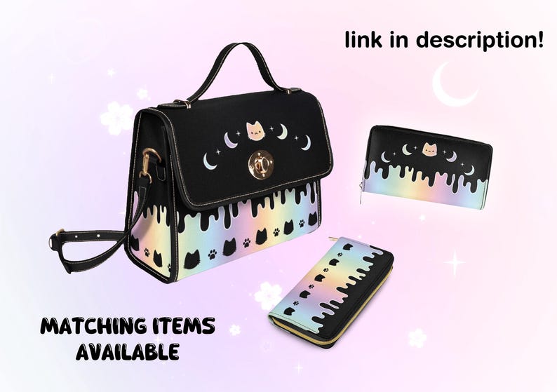 May include: Black satchel bag with a rainbow drip design and a cat face with crescent moons. The bag has a gold clasp and a matching wallet with the same design.