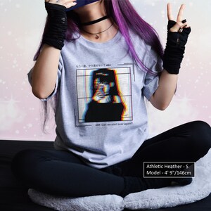 K&ouml;nnte beinhalten: Graues T-Shirt mit einem Grafikdruck einer Frau mit Glitch-Effekt. Der Text auf dem Shirt lautet "もう一度、やり直せない Can we start over again?" Das Model ist 1,46 m gro&szlig; und tr&auml;gt Gr&ouml;&szlig;e S.