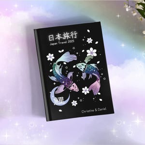 May include: Black journal with a Japanese design featuring two koi fish, cherry blossoms, and the text "日本旅行 Japan Travel 2025" and "Christine & Daniel".