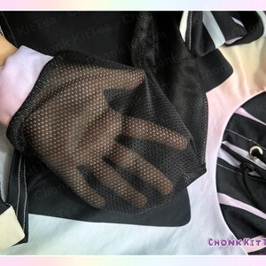 May include: Close-up of a black mesh glove over a light pink and white sleeve. The glove is part of a black and white patterned garment. The text "CHONKKITTEA" is visible in the lower right corner.